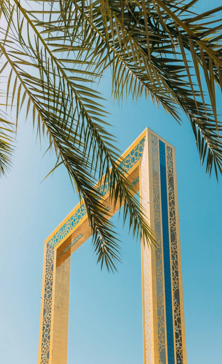 Vertical High quality photo. View Of Dubai Frame On Sunny Blue Sky Under Palm Branches. Dubai Frame